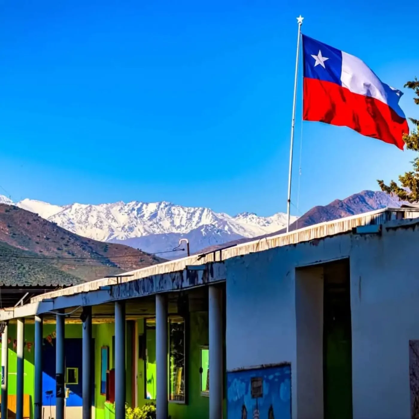 Pabellón de la escuela, bandera chilena y montañas al fondo